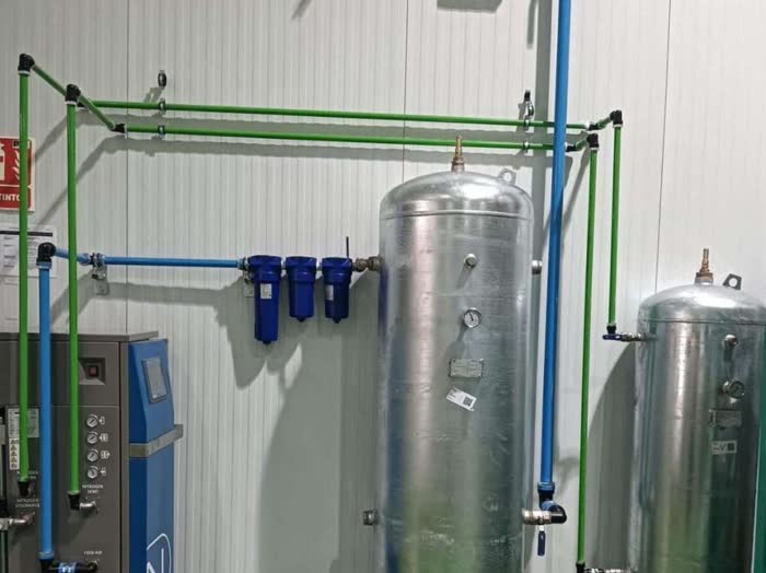 Sala de aire comprimido con depósitos, batería de filtros y tubería azul y verde
