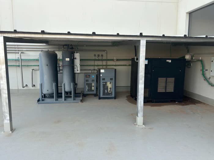 Sala de aire comprimido con depósitos, secador y compresor bajo una entreplanta