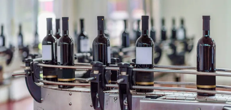 Botellas de vino avanzando por el carrusel de una línea de embotellado